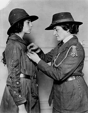 Juliette Gordon Low putting a badge on a girl scout.